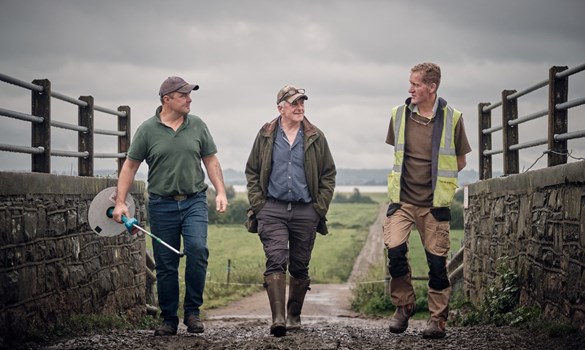 Three farmers at Lydney Park Farm walking together and talking.